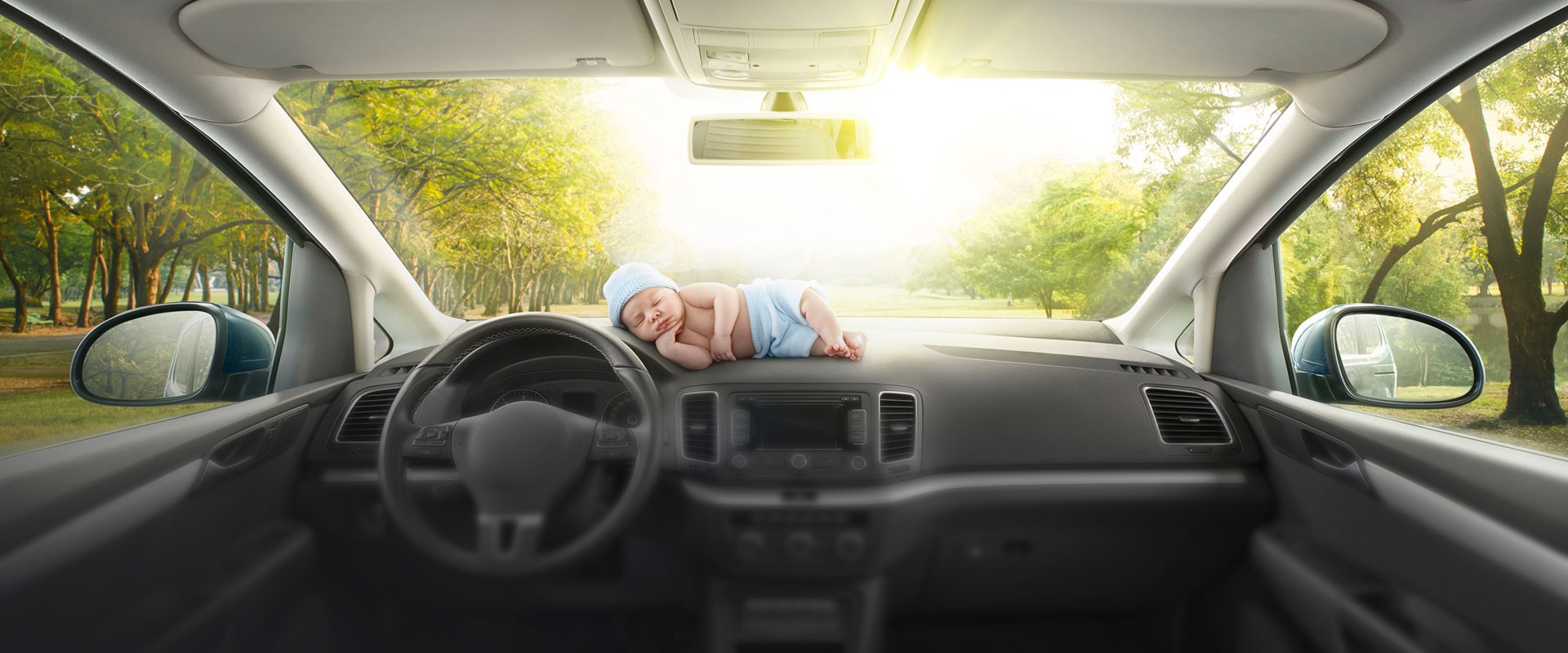 Schlafendes Baby liegt in stehendem Auto auf Armaturenbrett