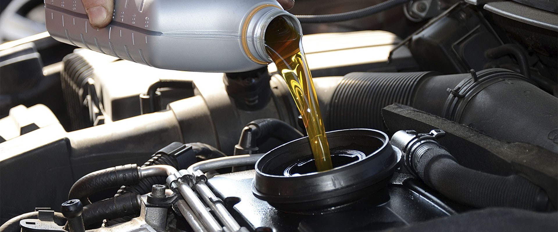 New gold-colored motor oil poured into a car engine