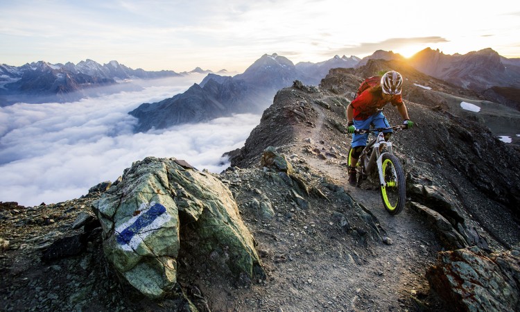 Bergkamm im Morgenlicht, über den ein Mountainbiker fährt