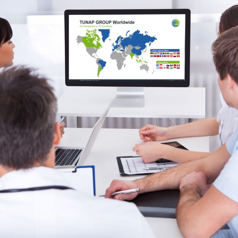 Persons in a meeting room looking at a monitor screen