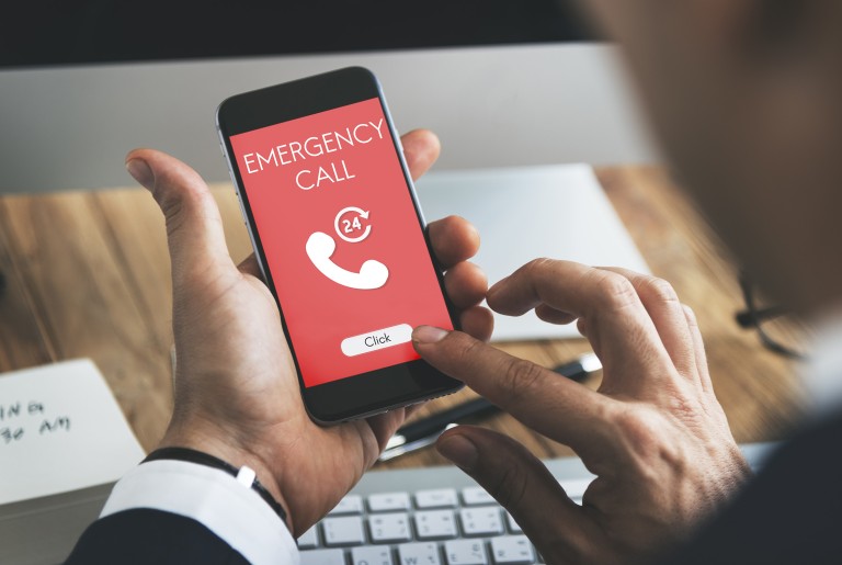 Giftnotruf Ein in Händen gehaltenes Smartphone, auf dessen rot-weißemDisplay die Wörter Emergency Call sichtbar sind