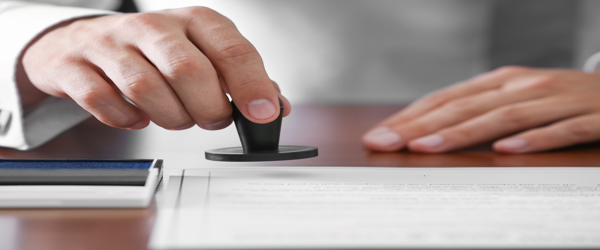 Großaufnahme einer Hand, die einen Stempel auf ein Blatt Papier senkt