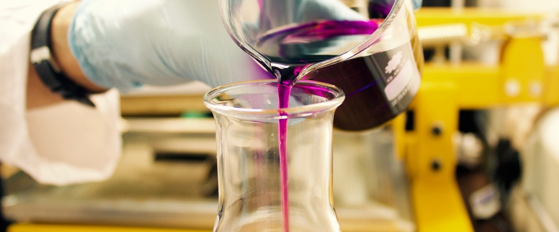 Smiling laboratory chemist wearing glasses and in the background a microscope and test tubes