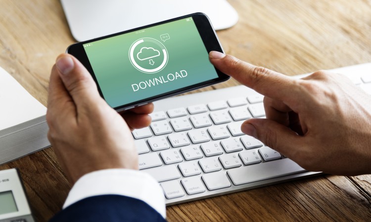 Man holding a mobile phone above keyboard